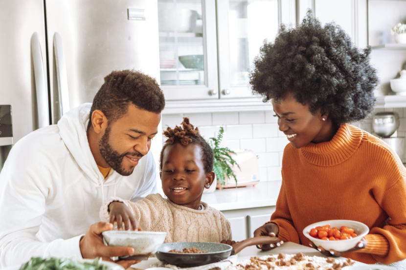 A family sitting around a table preparing their dinner.